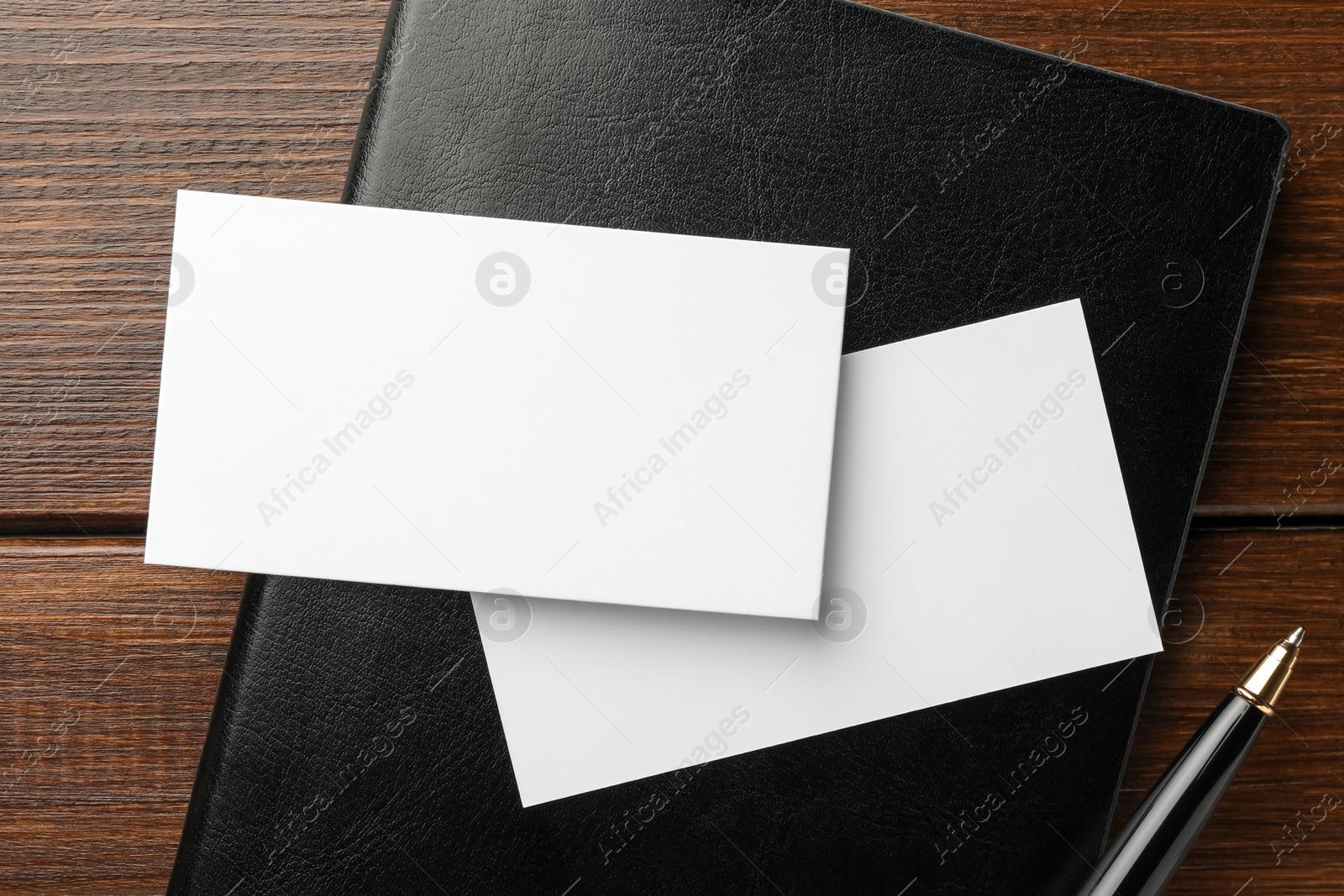 Photo of Blank business cards, notebook and pen on wooden table, flat lay. Mockup for design