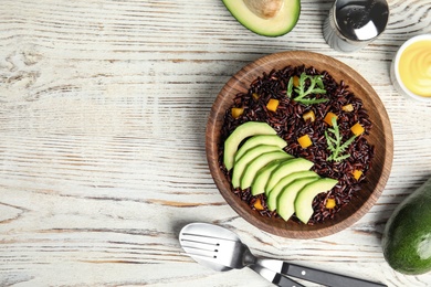 Flat lay composition with delicious cooked brown rice on white wooden table. Space for text