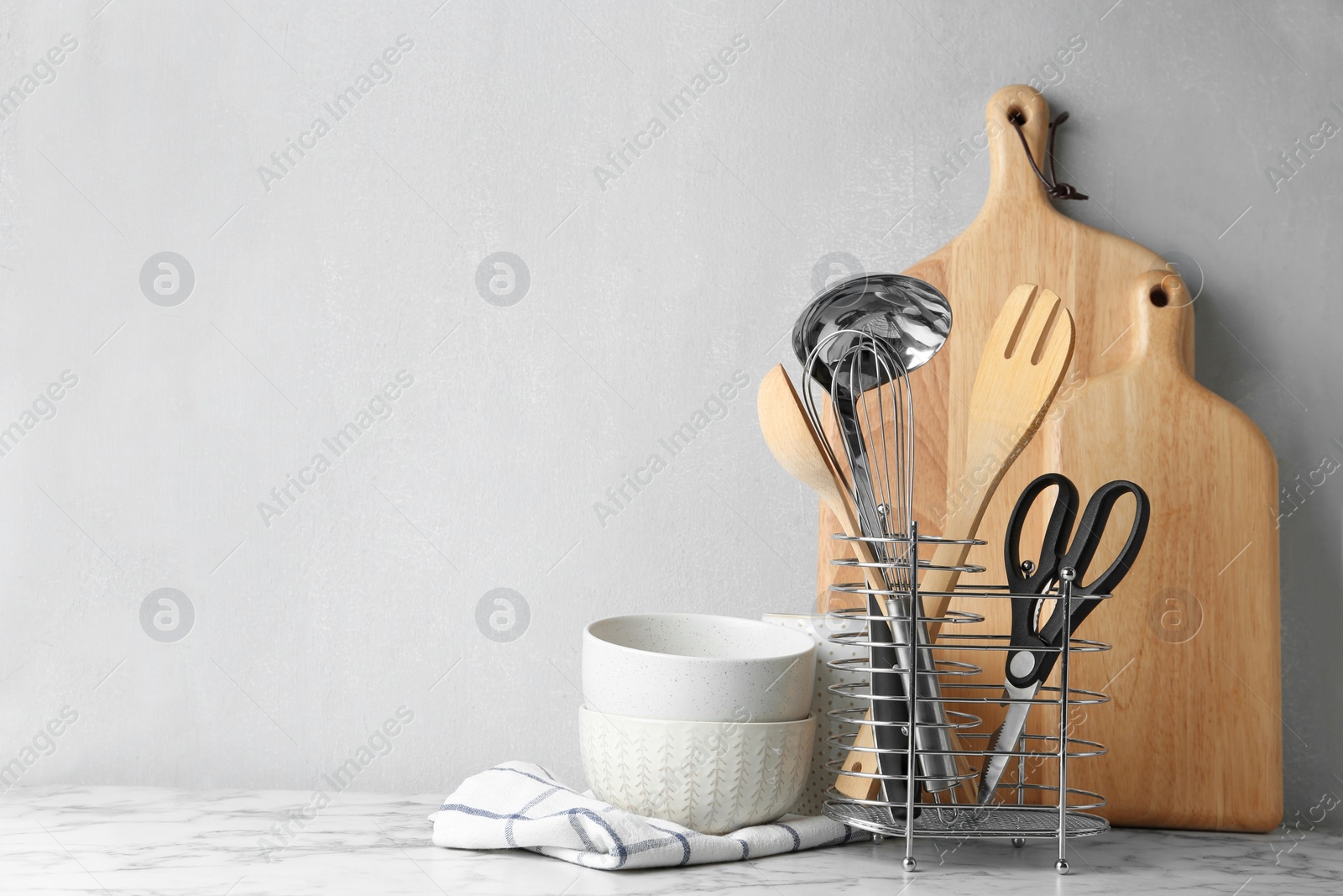 Photo of Different kitchen utensils on table against light background. Space for text