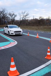 Photo of Modern car on driving school test track with traffic cones