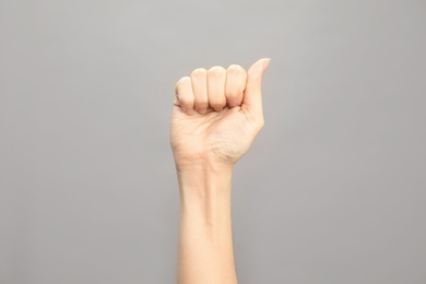 Photo of Woman showing A letter on grey background, closeup. Sign language