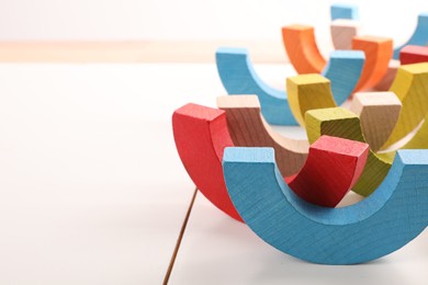 Photo of Motor skills development. Colorful wooden pieces of playing set on white table, closeup. Space for text