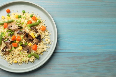 Photo of Delicious bulgur with vegetables and mushrooms on light blue wooden table, top view. Space for text