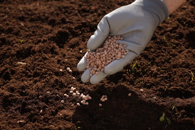 Photo of Man fertilizing soil, closeup. Space for text