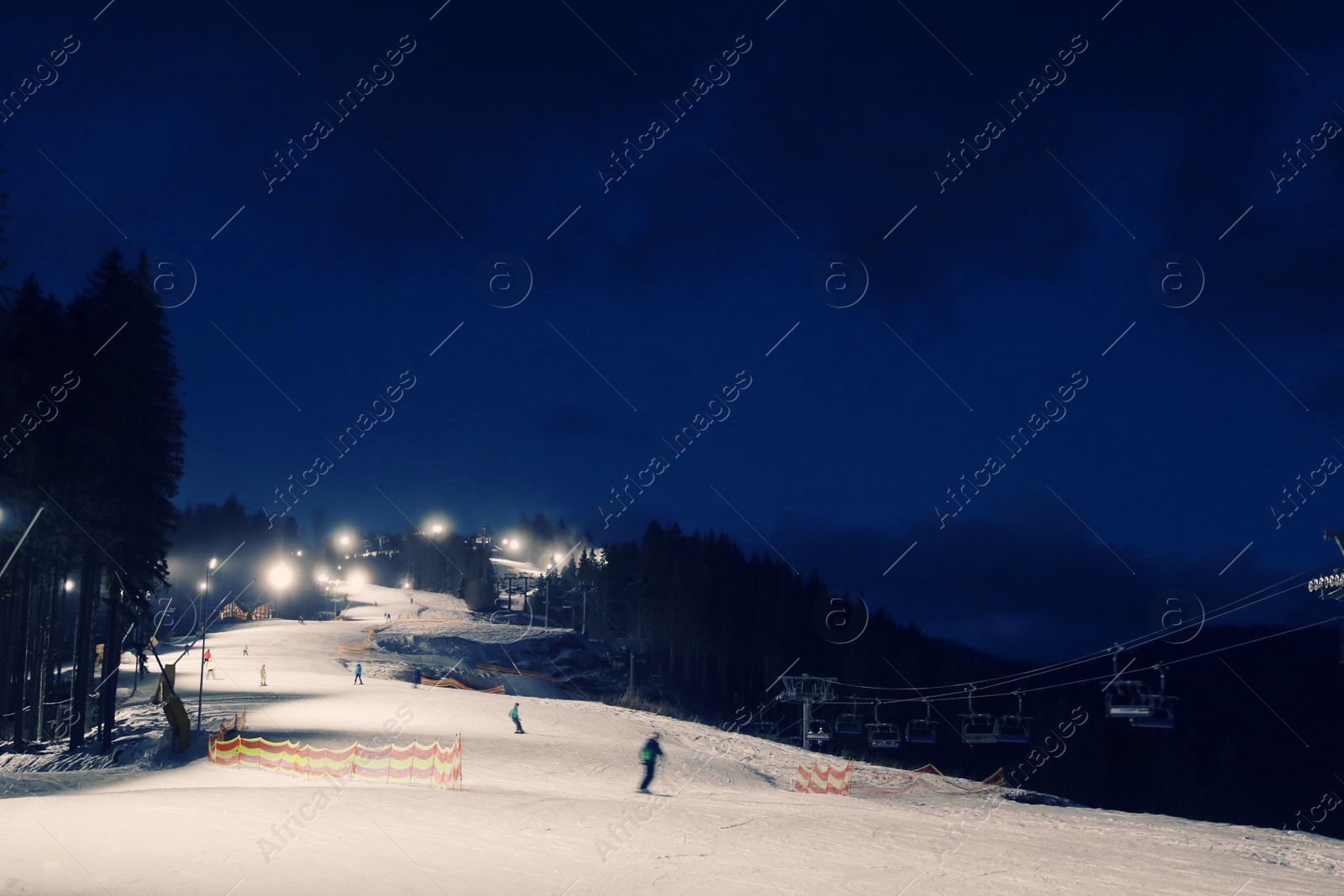 Photo of People skiing on snowy piste at night. Winter vacation