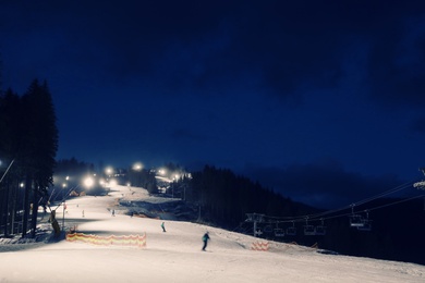 Photo of People skiing on snowy piste at night. Winter vacation