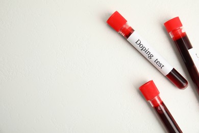Photo of Test tubes with blood samples and space for text on beige background, flat lay. Doping control