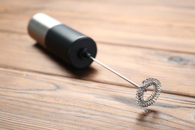 Photo of Black milk frother wand on wooden table, closeup