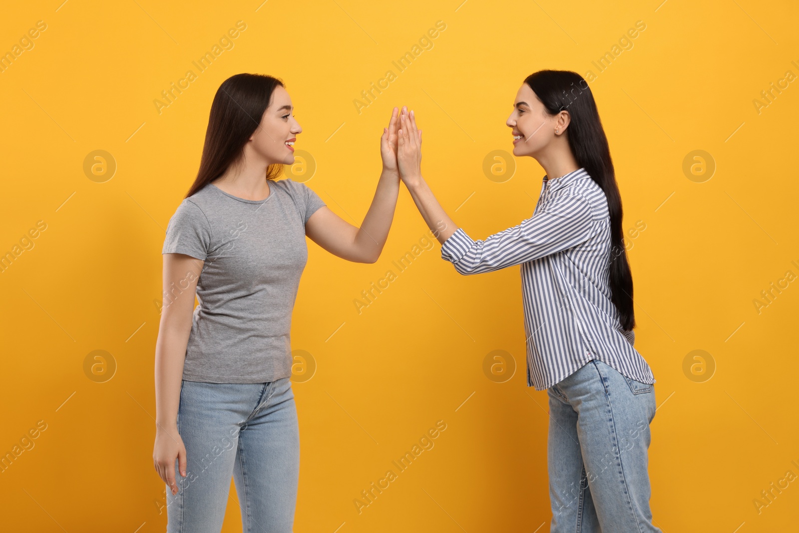 Photo of Women giving high five on orange background