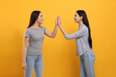 Photo of Women giving high five on orange background