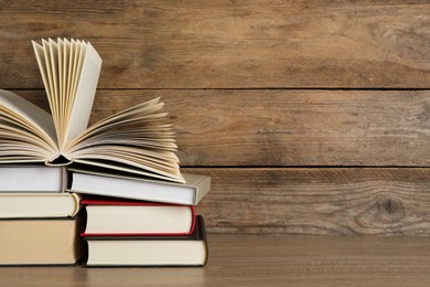 Stack of hardcover books on wooden table, space for text