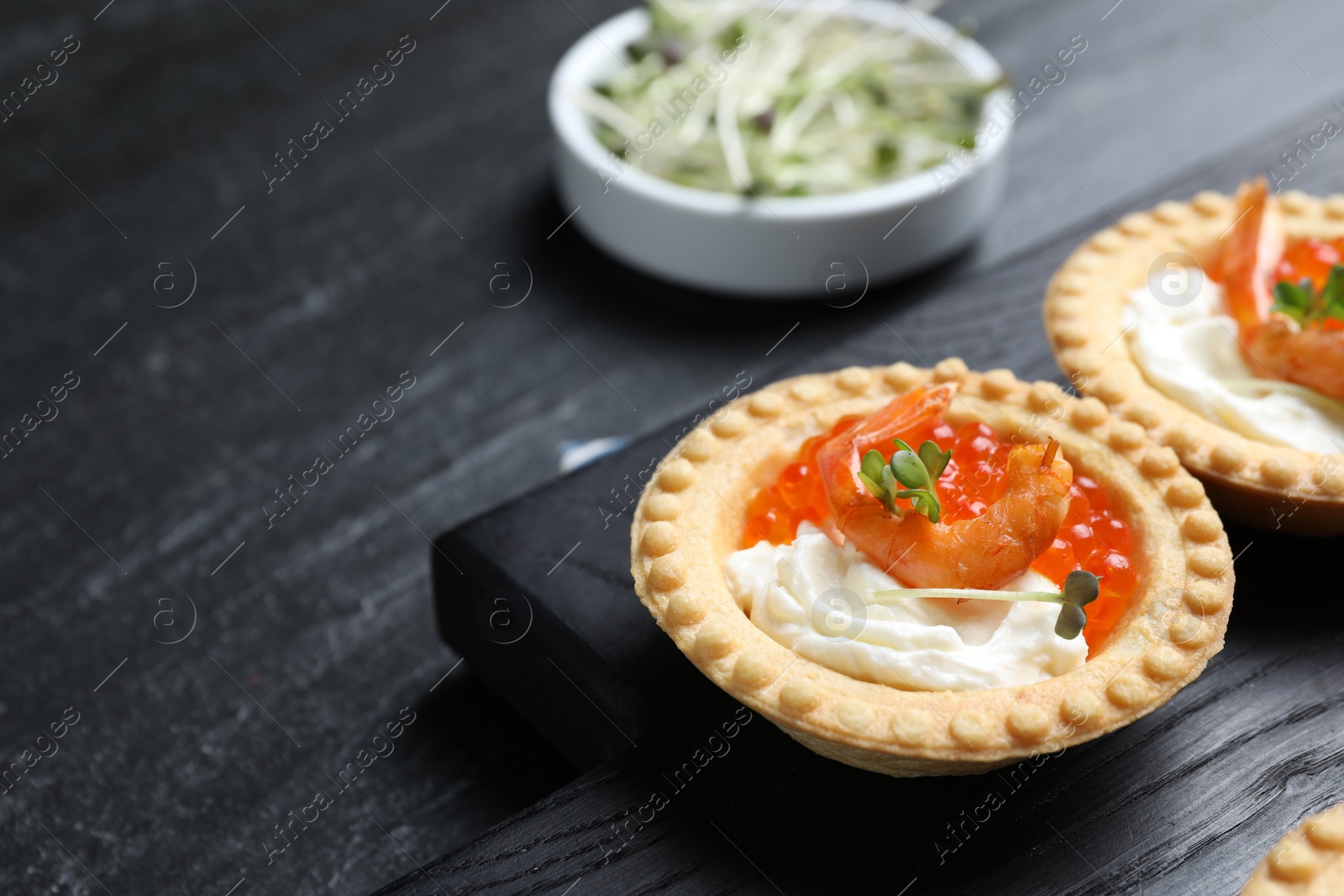 Photo of Delicious canapes with shrimps, red caviar and cream cheese on dark table, closeup