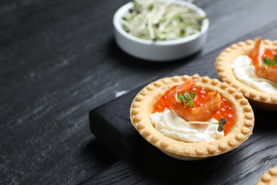 Delicious canapes with shrimps, red caviar and cream cheese on dark table, closeup