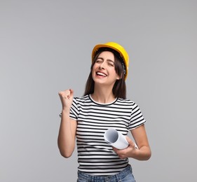 Architect with hard hat and draft on light grey background