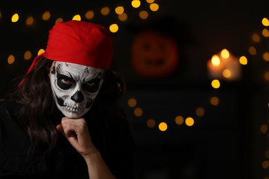 Man in scary pirate costume with skull makeup against blurred lights indoors, space for text. Halloween celebration