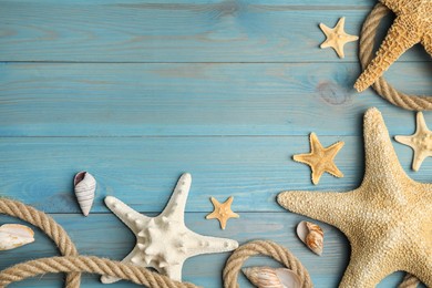 Beautiful sea stars, shells and rope on blue wooden background, flat lay. Space for text