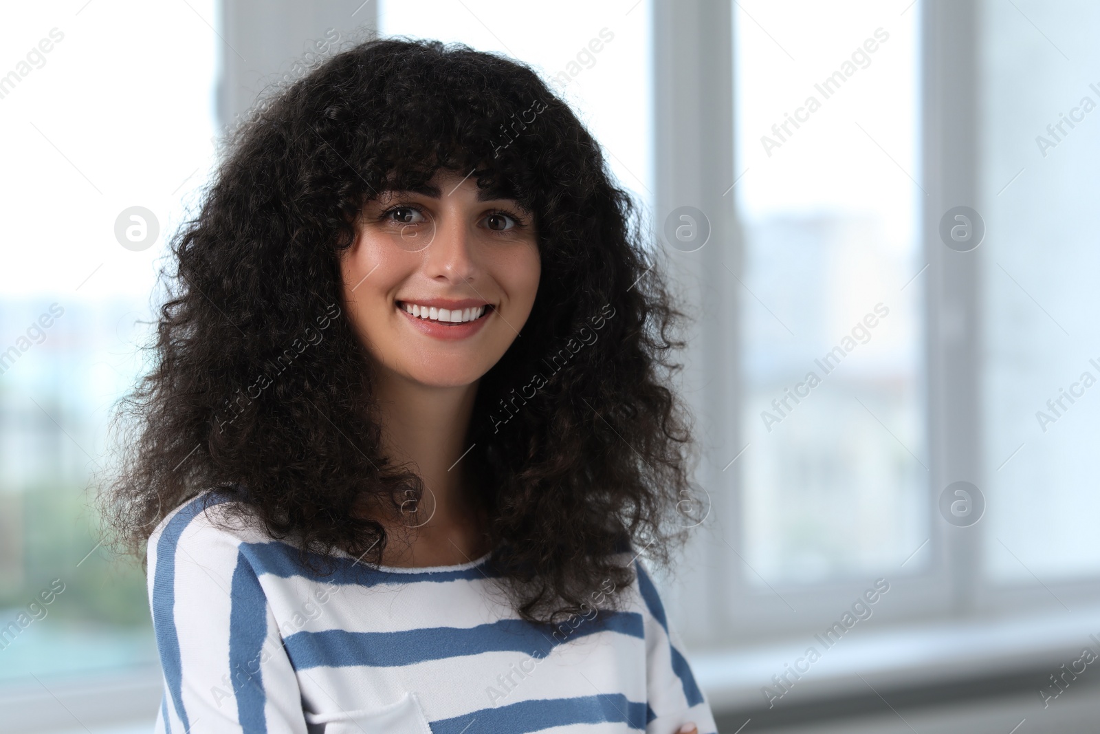 Photo of Portrait of beautiful woman in glasses indoors. Attractive lady with curly hair looking into camera. Space for text