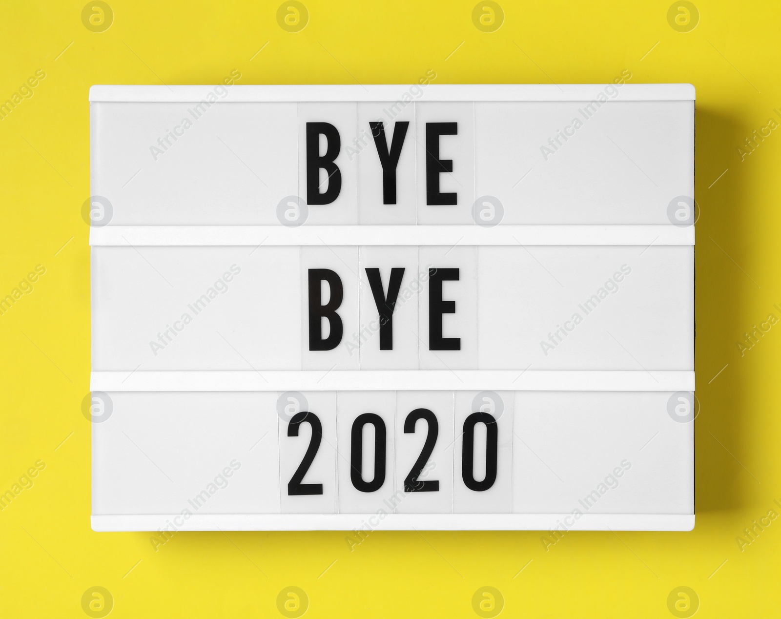 Photo of Lightbox with phrase Bye Bye 2020 on yellow background, top view