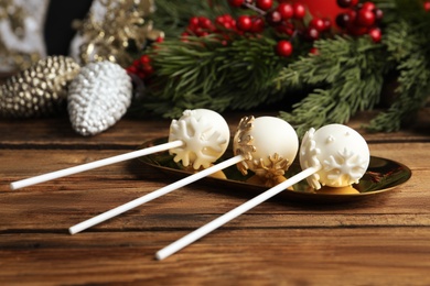 Photo of Delicious Christmas themed cake pops and festive decor on wooden table