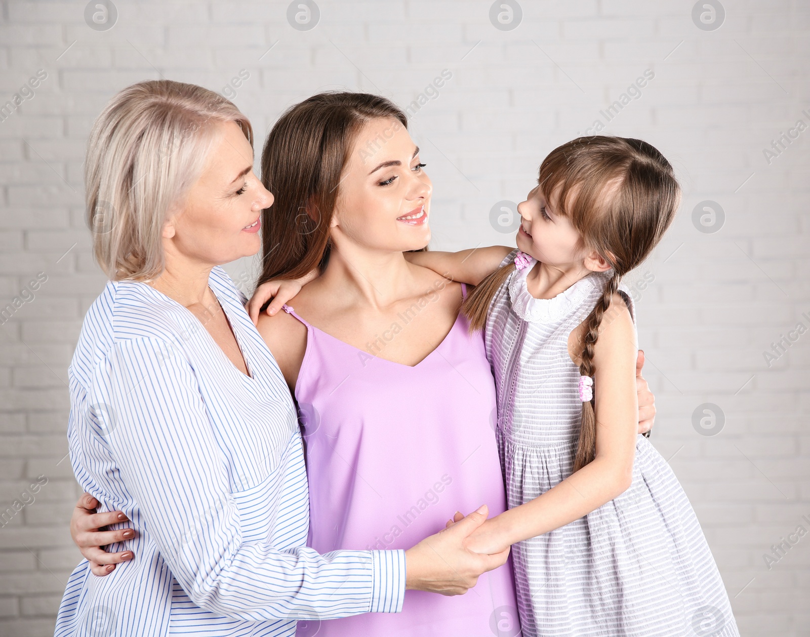 Photo of Beautiful mature woman with daughter and grandchild near brick wall