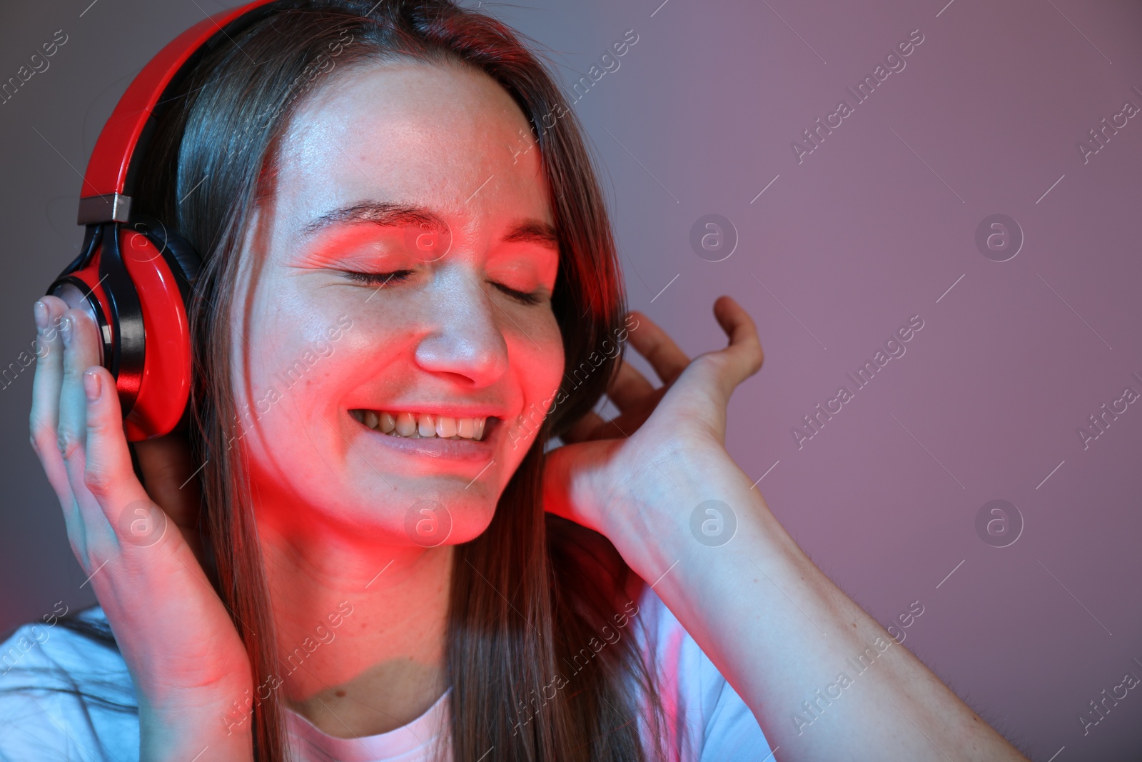 Photo of Portrait of beautiful woman with headphones on color background, space for text