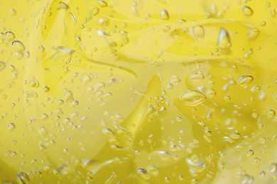 Photo of Pure transparent cosmetic gel on yellow background, closeup