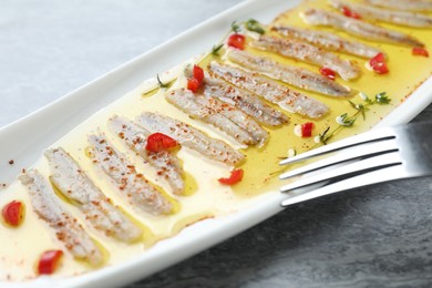 Photo of Tasty pickled anchovies with spices on gray table, closeup