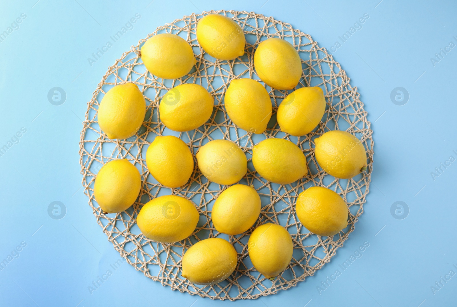 Photo of Ripe fresh lemon fruits on light blue background, top view