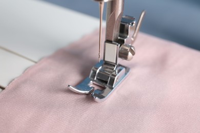 Photo of Sewing machine with color fabric on light background, closeup