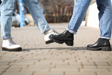 Photo of People greeting each other by bumping feet instead of handshake outdoors, closeup