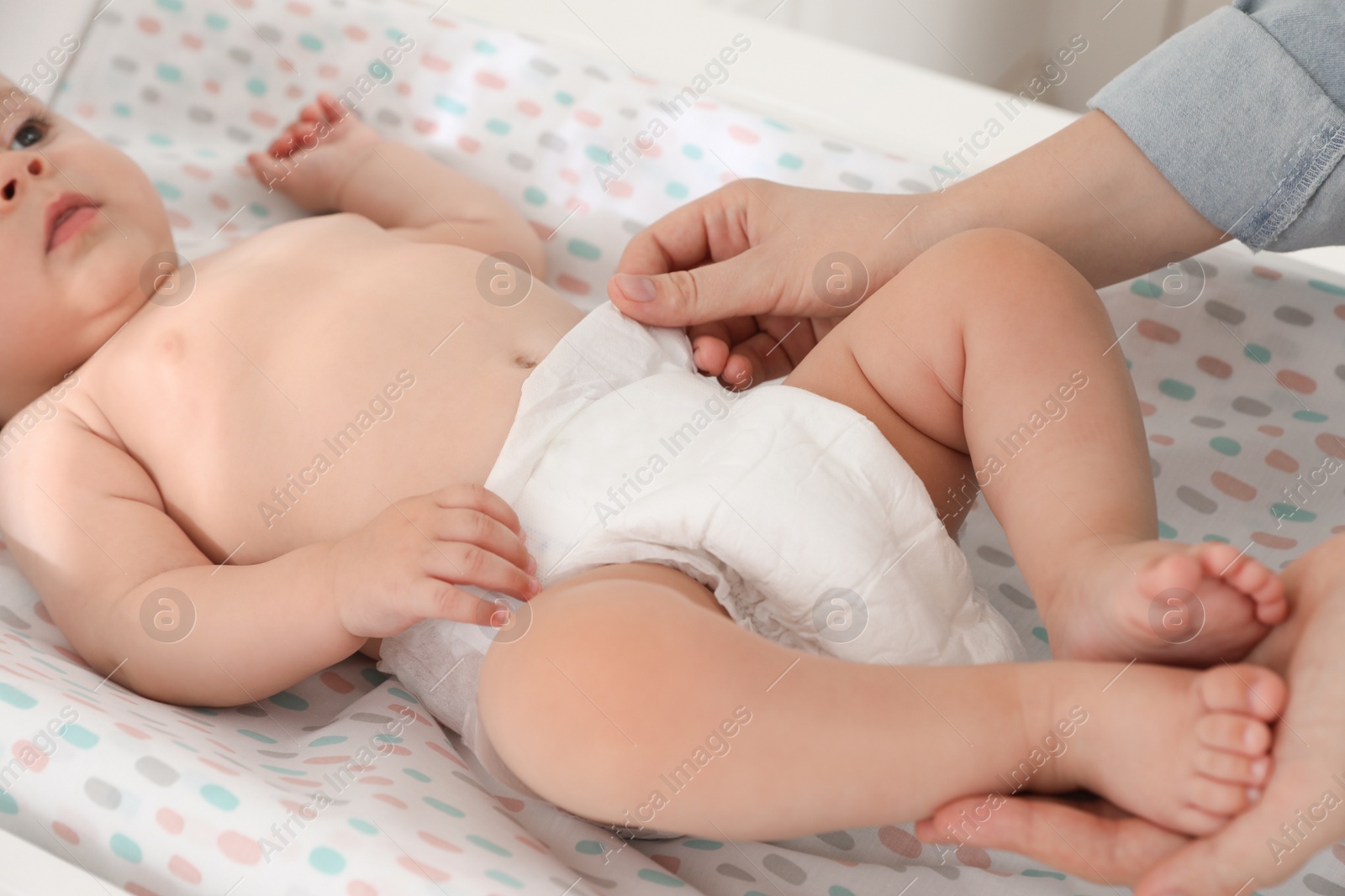 Photo of Mother changing baby's diaper on table at home, closeup