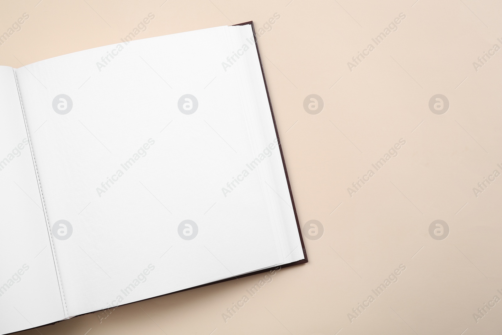 Photo of Open photo album on beige background, top view. Space for text