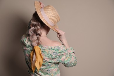 Photo of Young woman with hat and stylish bandana on beige background, back view. Space for text