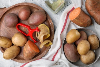 Photo of Different types of fresh potatoes on white textured table, flat lay