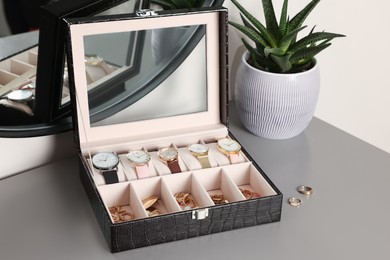 Photo of Elegant jewelry box with expensive wristwatches and beautiful bijouterie on grey table