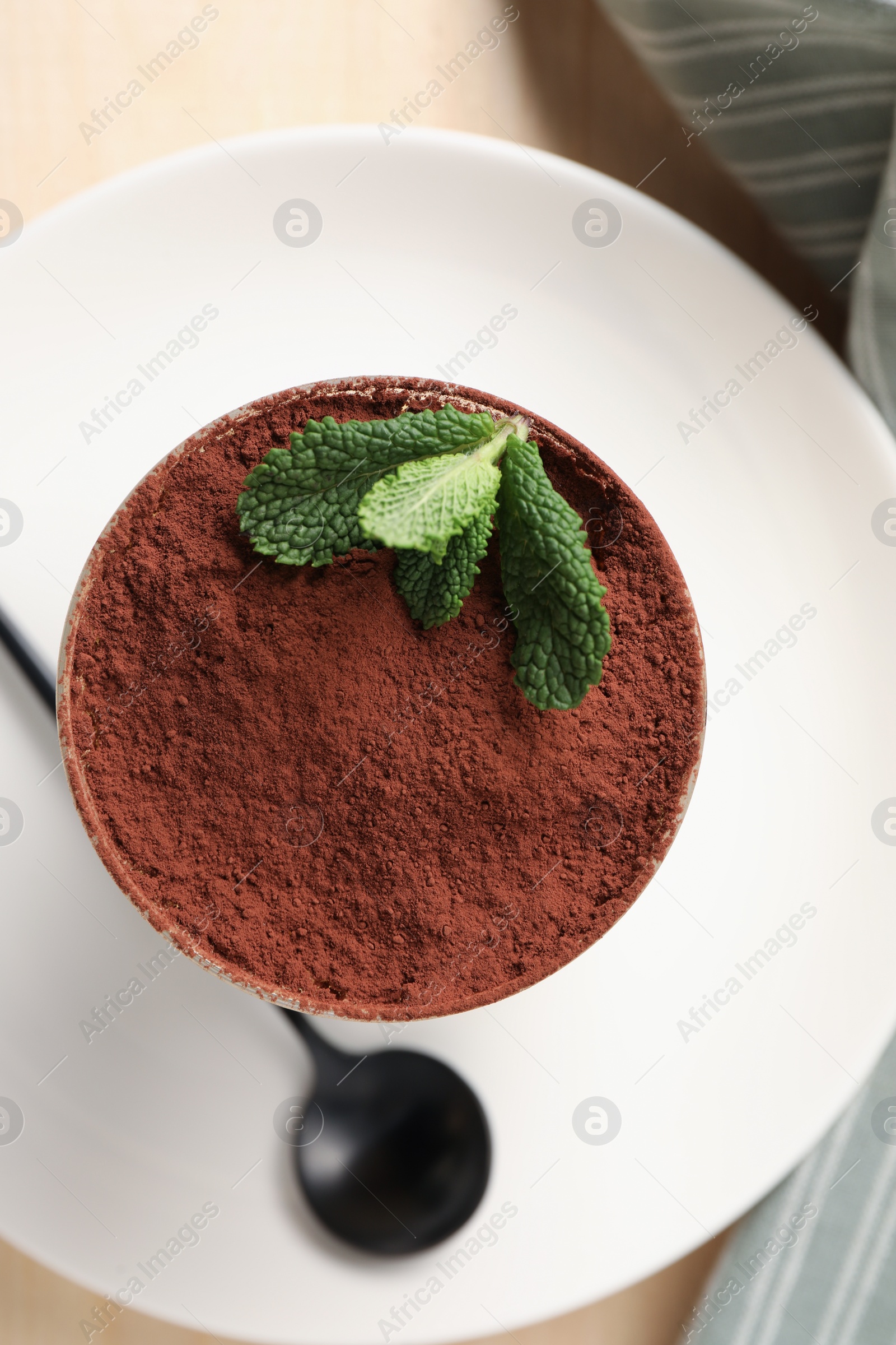 Photo of Tasty tiramisu and mint in glass on light wooden table, top view