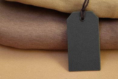 Photo of Garment with cardboard tag on kraft paper sheet, closeup. Space for text