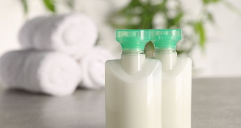 Photo of Mini bottles of cosmetic products against blurred background, closeup. Space for text