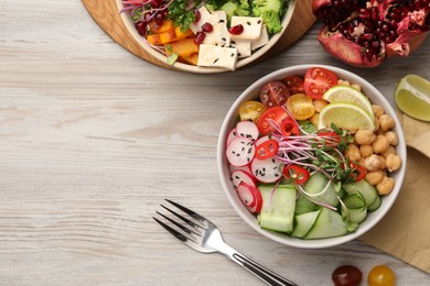 Photo of Bowl with many different vegetables on white wooden table, flat lay and space for text. Vegan diet