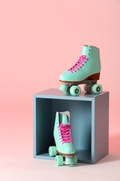 Photo of Pair of vintage roller skates and storage cube on color background