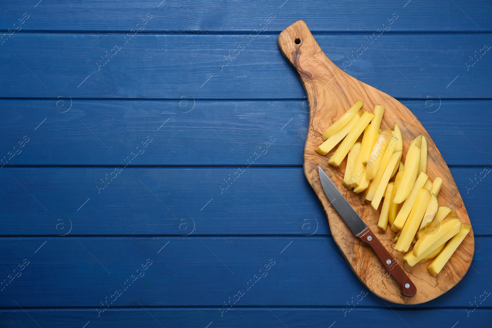 Photo of Cut raw potatoes and knife on blue wooden table, top view. Space for text. Cooking delicious French fries