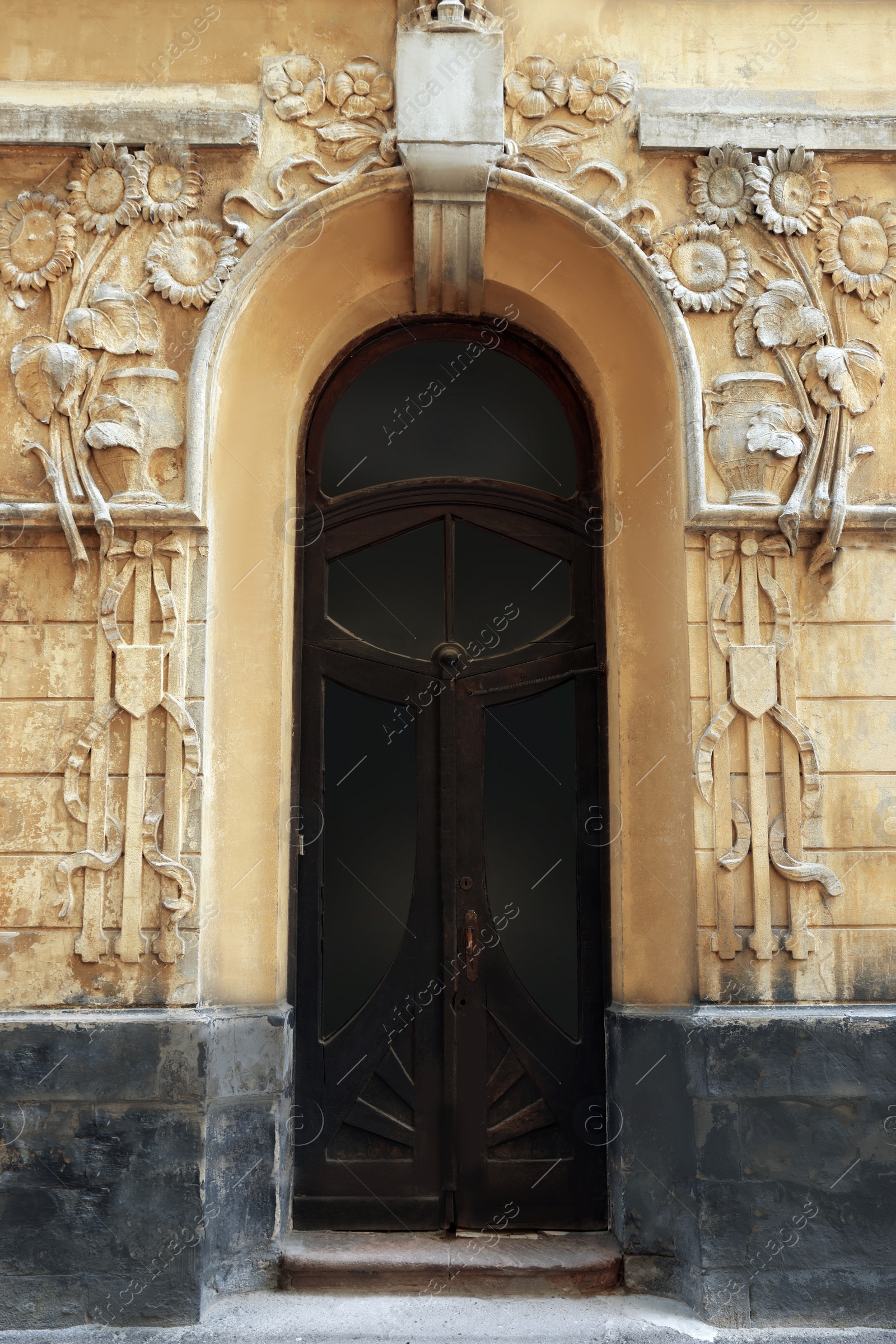 Photo of Entrance of house with arched wooden door and beautiful moldings