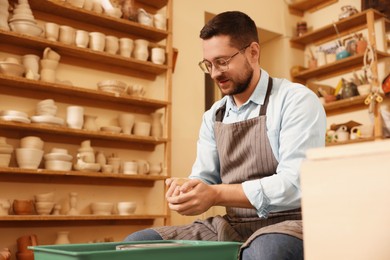 Photo of Man crafting with clay indoors, low angle view