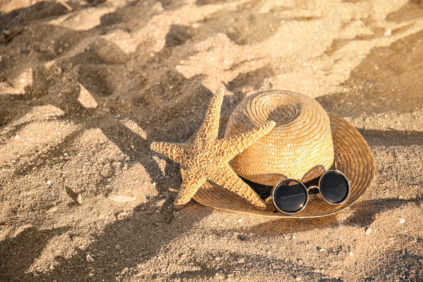 Photo of Straw hat, starfish and sunglasses on beach sand. Summer vacation