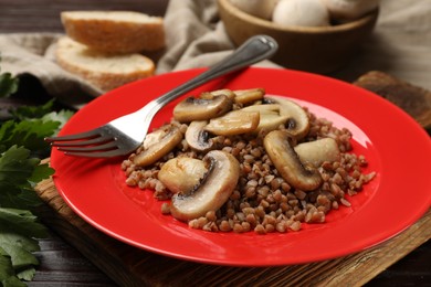 Tasty buckwheat with mushrooms and fork on table, closeup