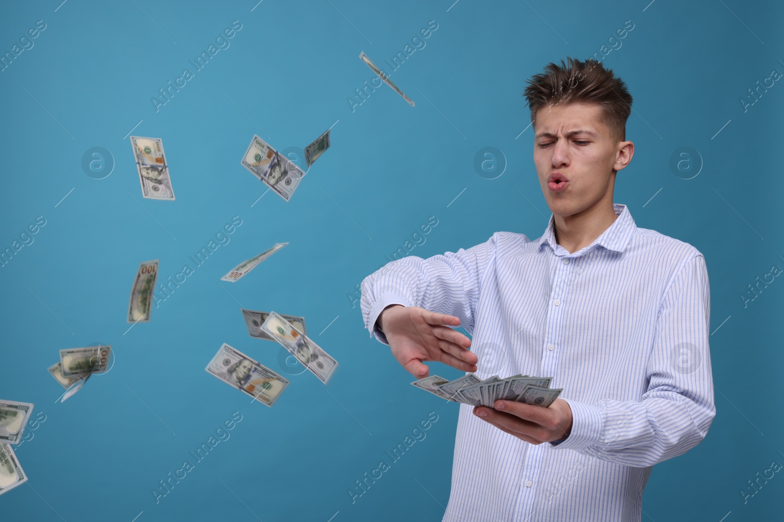 Photo of Handsome man throwing dollar banknotes on light blue background