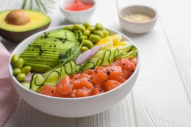 Photo of Delicious poke bowl with avocado, fish and edamame beans on white wooden table, closeup. Space for text