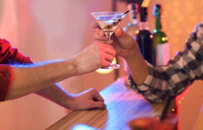Photo of Young man taking martini cocktail from barman in pub, closeup