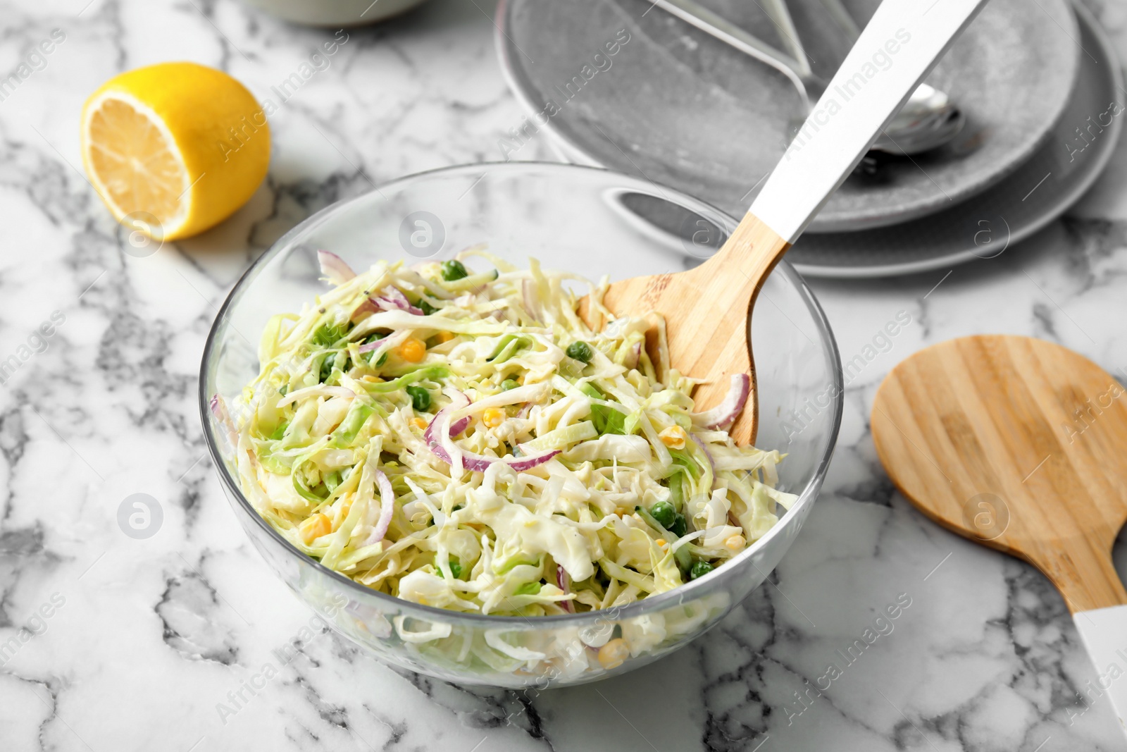 Photo of Bowl with fresh cabbage salad on marble table in kitchen