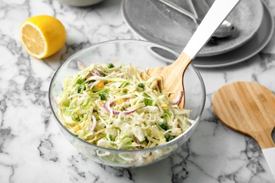 Bowl with fresh cabbage salad on marble table in kitchen